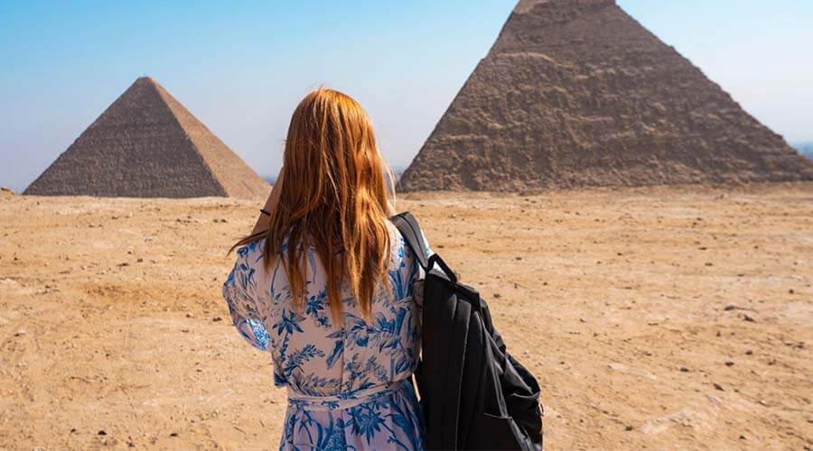 Image of a foreign tourist carrying a bag in front of the pyramids